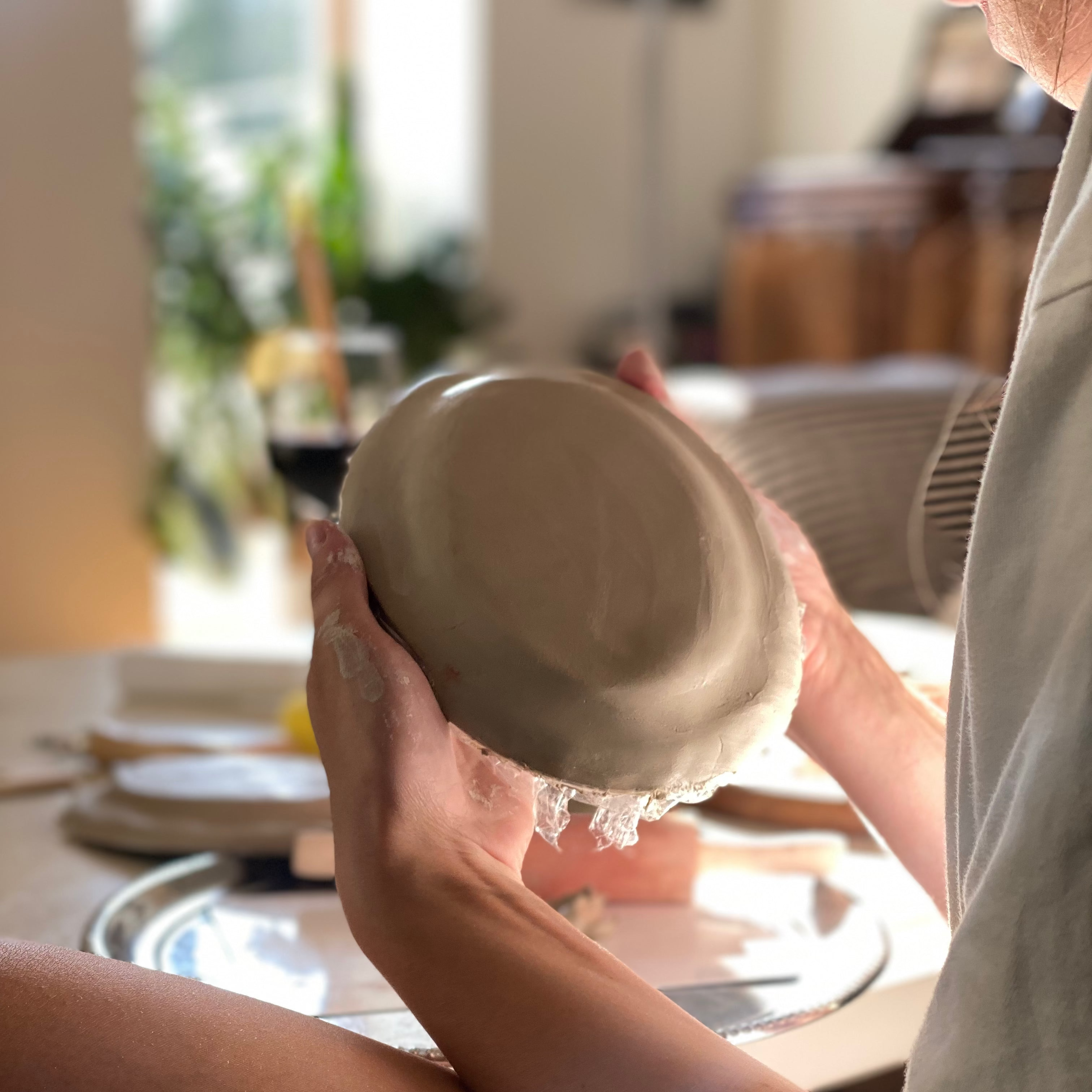 Person creating a ceramic plate in a living room setting